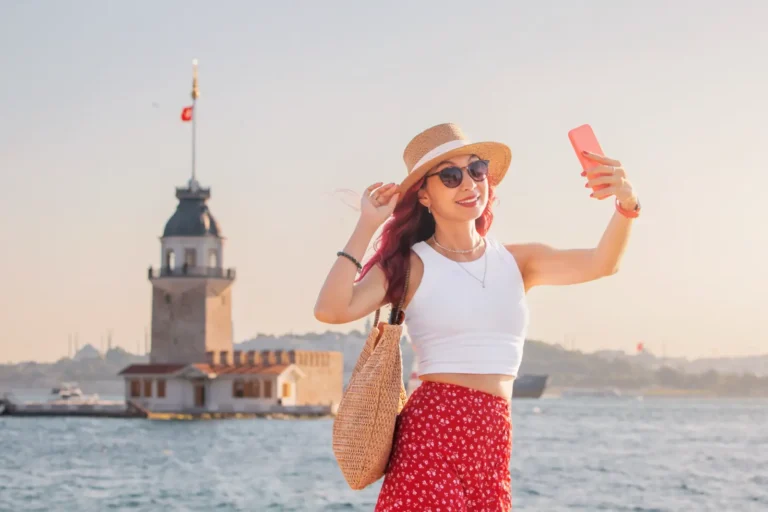 Travel influencer taking a selfie in front of Istanbul's Maiden's Tower on the Bosphorus during golden hour.