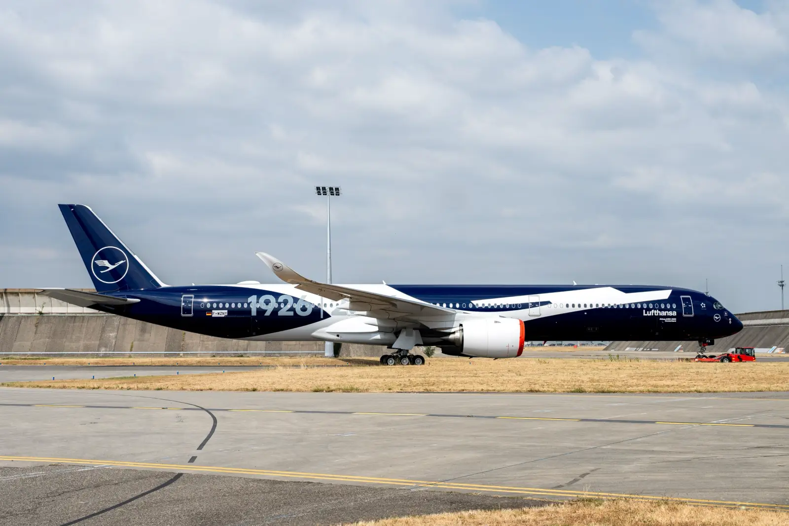 Lufthansa's first Airbus A350-1000, registered F-WZNY, sits on the tarmac in Toulouse featuring a blue and white centenary livery marking "1926" and the airline's 100th anniversary.