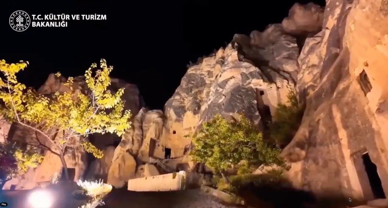 Ancient rock carved cave dwellings illuminated at night in Cappadocia, Türkiye, showcasing the region's historic landscape and evening tourism experience