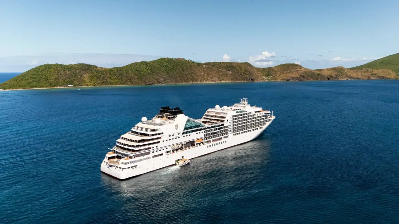 Seabourn Celebrates The Line’s 40Th Anniversary With 54 Special Voyages In 2028 5 A Seabourn cruise ship sails through the Caribbean near a lush tropical island during a yacht-style luxury voyage.