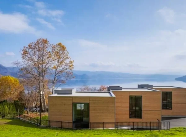 Home 2 Modern lakeside hotel overlooking Lake Tōya in Hokkaido with contemporary architecture and scenic mountain views.